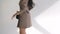 Beautiful brunette posing and spinning in a white room. A woman in a smart, strict dress and with a black handbag looks