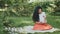 Beautiful brunette sits on plaid in park and writes poems on paper