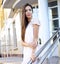 Beautiful brunette stands on the steps, a shopping center, in pink dress, soft sensual look, sunny summer day, fashion