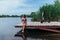 A beautiful brunette in a swimsuit sunbathes on a wooden bridge and there is a scooter nearby. Ecology and health care concept