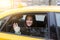 Beautiful brunette waving hand from open window of taxi