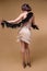 Beautiful brunette woman in boa from ostrich feathers is dancing on beige background