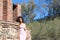 Beautiful brunette woman with curly hair among the ruins of an old abandoned building. The woman is dressed in an elegant pink and