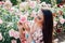 Beautiful brunette woman in a dress with flowers with fragrant roses