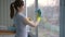 Beautiful brunette woman in gloves washes windows