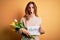 Beautiful brunette woman holding best mom message and tulips celebrating mothers day scared in shock with a surprise face, afraid