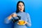 Beautiful brunette woman holding french coffee maker pouring coffee on cup making fish face with mouth and squinting eyes, crazy