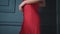Beautiful brunette woman lady in a silk red dress evening make-up leans against a blue wall to bask in a luxurious life glamorous