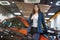 Beautiful brunette woman manager in business suit standing in electric car dealership center showing like sign