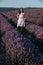 beautiful brunette woman standing in lavender purple flowers walk trip