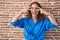 Beautiful brunette woman standing over bricks wall doing peace symbol with fingers over face, smiling cheerful showing victory