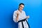 Beautiful brunette young woman wearing karate fighter uniform with black belt very happy and excited doing winner gesture with