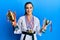 Beautiful brunette young woman wearing karate fighter uniform and medals holding trophy smiling with a happy and cool smile on