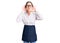 Beautiful brunette young woman wearing professional waitress apron trying to hear both hands on ear gesture, curious for gossip