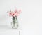Beautiful bunch of tulips in glass vase on white table at wall. Flowers in interior design.