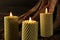 Beautiful burning beeswax candles on snag, closeup