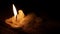 Beautiful burning candle with flame from wick and wax shining light into the darkness on wooden table background with copy space f