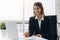 Beautiful business lady is looking at laptop and smiling while working in office. Concentrated on work