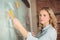 Beautiful businesswoman sticking notes on board in office