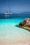 Beautiful calm azure blue lagoon with sailing catamaran yacht boat at anchor. Pure white pebble beach with rocks in the