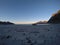 Beautiful calm blue waves hitting white frozen sandy beach in late autumn in the arctic circle with deep mountain and open sea vie