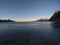 Beautiful calm blue waves hitting white frozen sandy beach in late autumn in the arctic circle with deep mountain and open sea vie