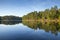 Beautiful calm northern Minnesota lake under blue sky with trees along the shore in afternoon sunlight