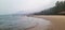 A beautiful calm scenery of a beach with fog covering the mountains
