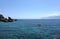 Beautiful calm sea and rocks in front and high mountains in haze at far