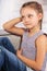 Beautiful calm thinking kid girl sitting on the bench in blue jeans and fashion blouse looking happy. Closeup portrait