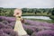 Beautiful carefree woman in dress and hat with a basket of flowers in a field of fragrant lavender. Soft selective focus, art