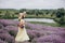 Beautiful carefree woman in dress and hat with a basket of flowers in a field of fragrant lavender. Soft selective focus, art
