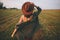 Beautiful carefree woman in hat walking in evening summer field. Relaxing in countryside. Happiness