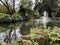 Beautiful cascading fountain in a garden pond surrounded by green trees. Concept of relaxation and happiness