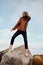 Beautiful casual Asian girl in knitted sweater posing on big stones on seaside