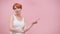 Beautiful casualy dressed middle aged redhead woman pointing finger on empty space isolated on pink background