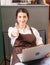 Beautiful caucasian barista woman sits relaxing and gives thumbs up while using laptop in breaking time at coffee shop