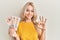 Beautiful caucasian blonde girl holding 10 united kingdom pounds banknotes doing ok sign with fingers, smiling friendly gesturing