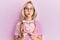Beautiful caucasian blonde girl holding piggy bank with glasses puffing cheeks with funny face