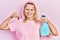 Beautiful caucasian blonde woman holding cockroach and pesticide sprayer smiling with a happy and cool smile on face