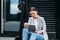 Beautiful caucasian female sitting on parked electric scooter on street holding a digital tablet