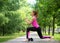 Beautiful caucasian fit woman does deep lunge on paved path in public park outdoor in summer, selective focus.