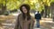 Beautiful Caucasian girl in elegant brown hat and coat posing on the background of autumn park. Positive European woman