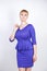 Beautiful caucasian girl with short hair and plus size body dressed in blue medium length dress in business style with peplum at t