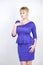 Beautiful caucasian girl with short hair and plus size body dressed in blue medium length dress in business style with peplum at t