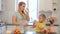 Beautiful caucasian Mom with long white hair pouring out a glass of milk for her cute son in yellow shirt. Modern