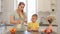 Beautiful caucasian Mom with long white hair pouring out a glass of milk for her cute son in yellow shirt. Modern