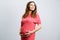 Beautiful caucasian pregnant girl  touching her belly and dreamily looking up. Pregnant young woman on grey background.