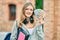 Beautiful caucasian student teenager using headphones holding canadian dollars at the city