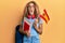 Beautiful caucasian teenager girl exchange student holding spanish flag angry and mad screaming frustrated and furious, shouting